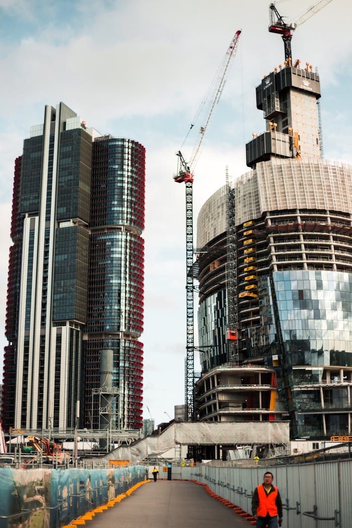 Dynamic cityscape featuring skyscrapers under construction and cranes in a bustling urban environment.