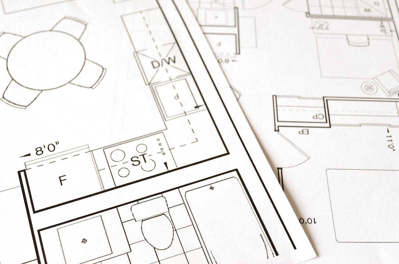 our-services-1 Close-up view of an architectural floor plan on paper showcasing detailed room layouts and measurements.