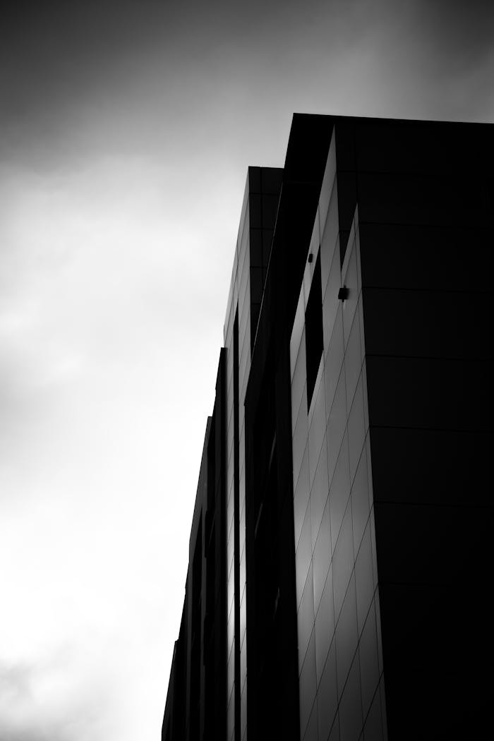 Black and white photo of a modern skyscraper against a dramatic sky.