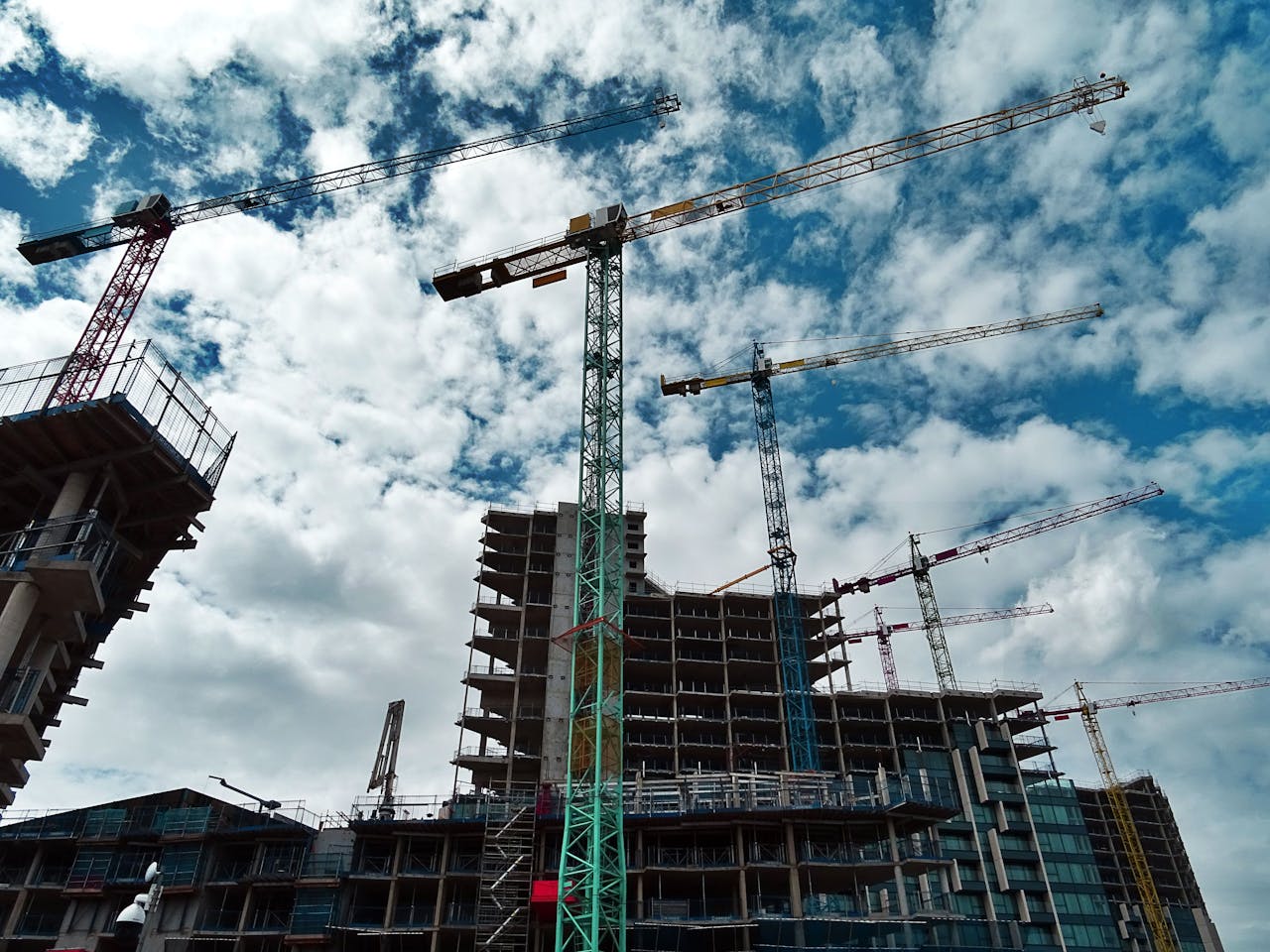 about-01 Urban construction site with numerous cranes framing rising skyscrapers against a blue sky.